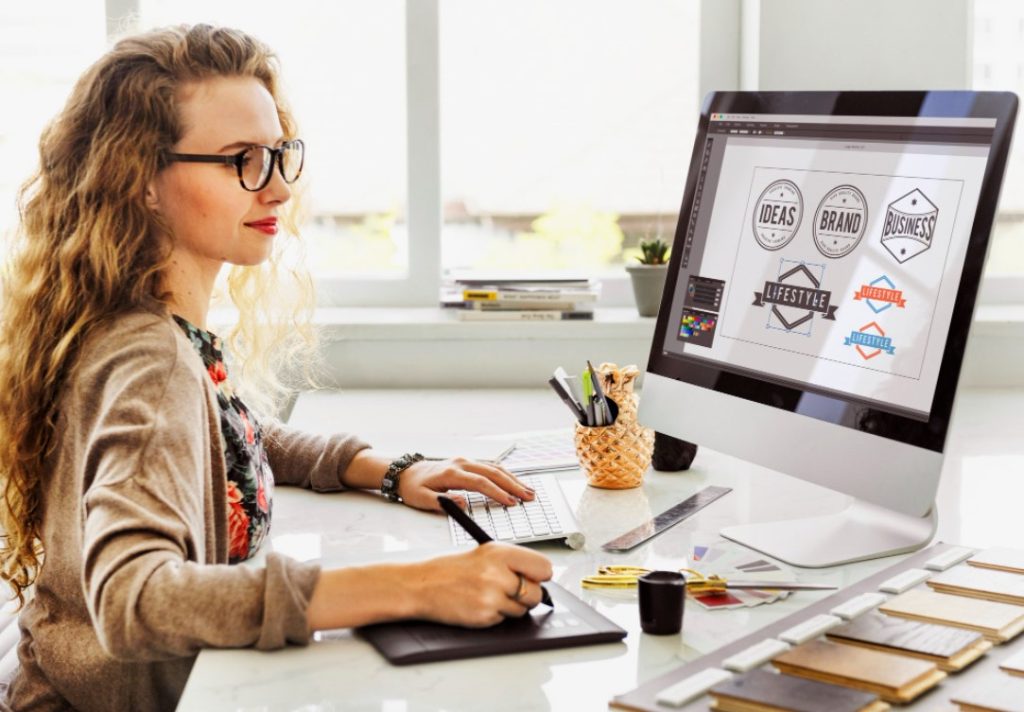 Designer usando um tablet gráfico para criar logotipos em um computador.