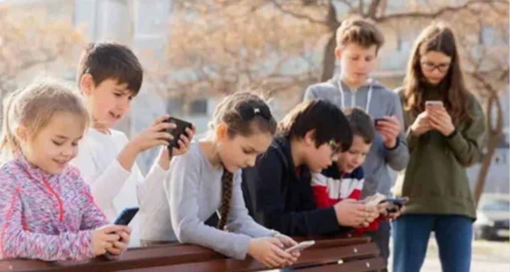 Crianças olhando para seus smartphones em um parque.