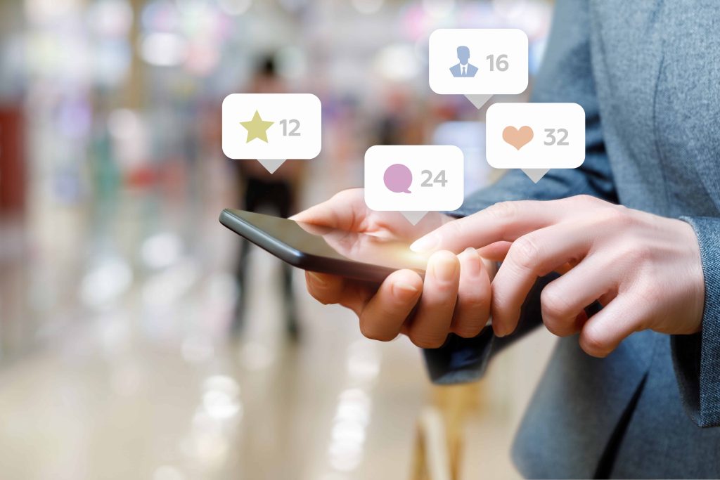 Três amigos olhando para um smartphone, com notificações de mídia social.