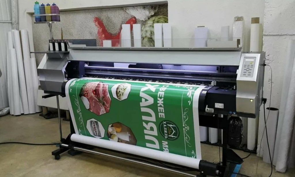 Plotter imprimindo um banner colorido em um ambiente de produção.