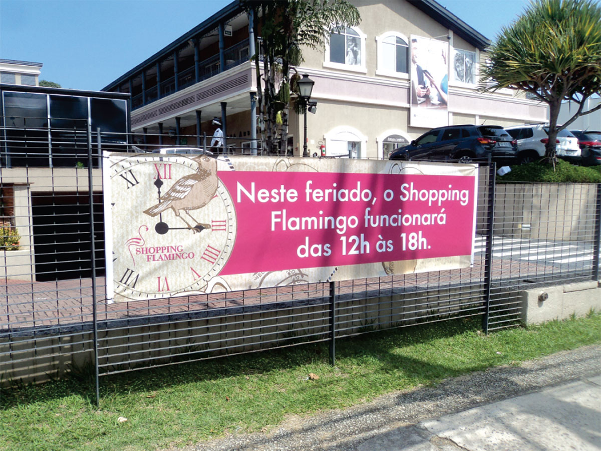 Banner promocional em uma cerca com relógio e ave.