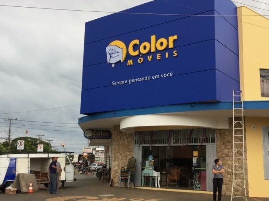 Fachada da loja Color Móveis com letreiro azul e logotipo de cadeira.