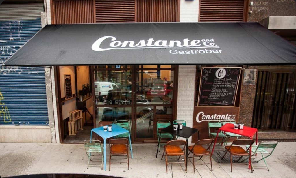 Fachada do gastrobar Constante and Co. com letreiro branco em fundo preto.
