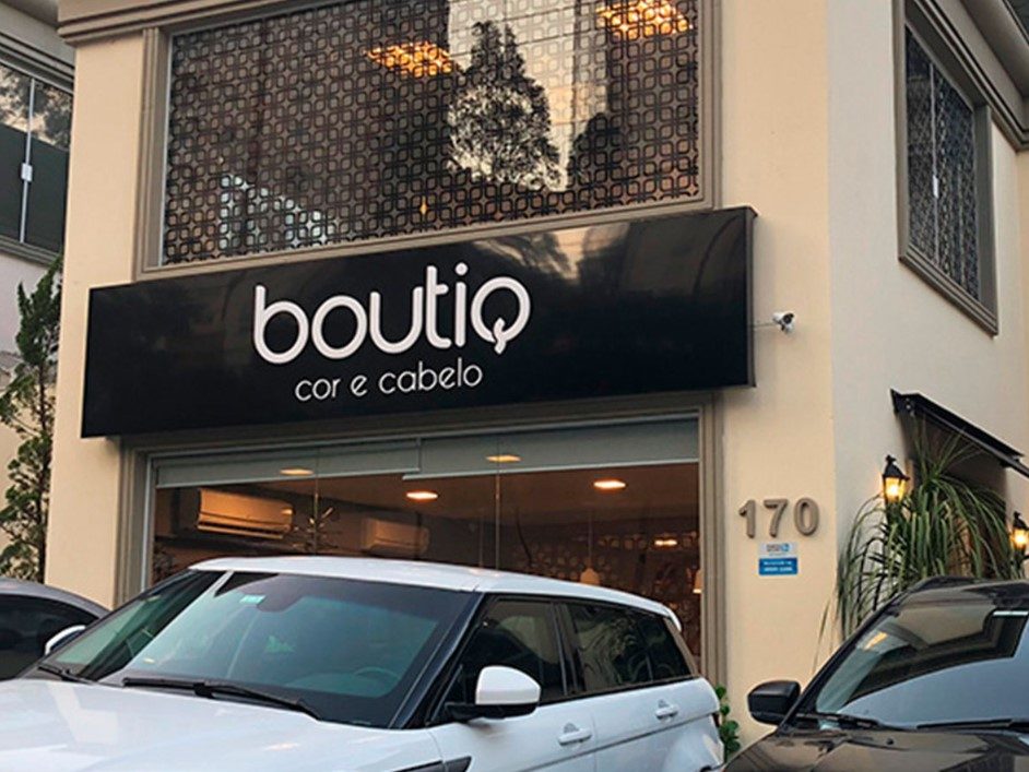 Fachada de um salão de beleza com letreiro "boutiq cor e cabelo," design moderno com grandes janelas.