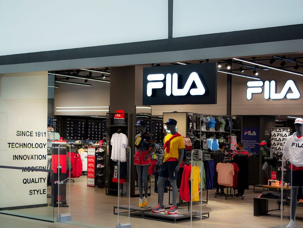 Fachada da loja FILA com design moderno e logotipo iluminado.