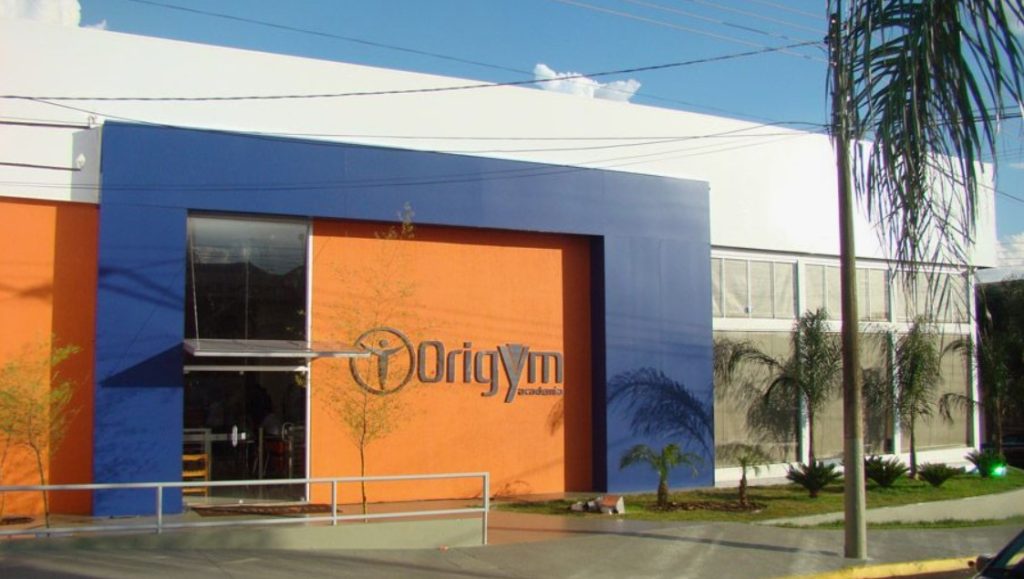 Fachada da Origym Academia com letreiro em laranja e azul.