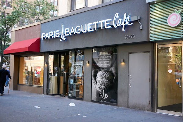 Fachada do Paris Baguette Café com letreiro iluminado e logo estilizado.