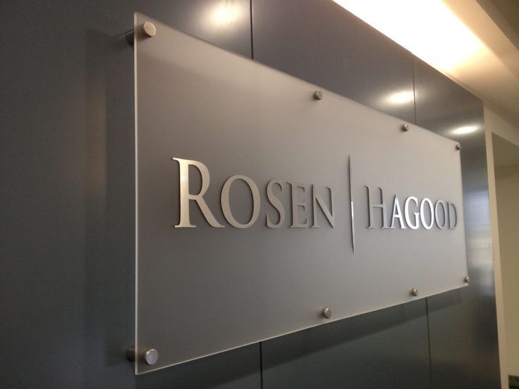 Placa de vidro fosco montada na parede, com letras metálicas \"ROSEN | HAGOOD\".