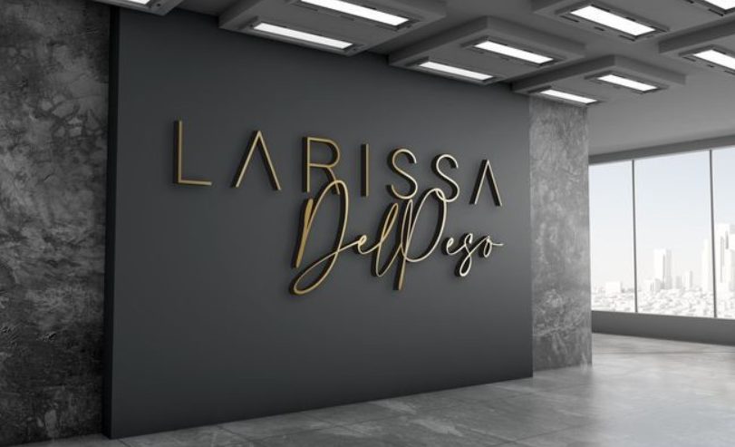 Parede interna escura com letreiro dourado \"LARISSA DelPeso\" em letras grandes.