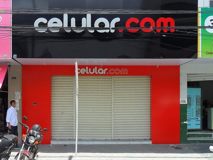 Loja Celular.com com fachada vermelha e placa preta e branca.