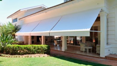 Casa moderna branca com elegantes toldos retráteis no pátio ensolarado.