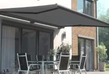 Casa moderna com pátio, toldo retrátil, elegante mesa e cadeiras.