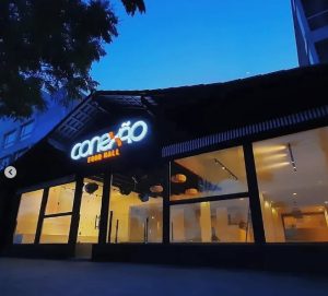 Fachada iluminada do "conexão FOOD HALL" em ambiente urbano moderno.