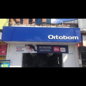 Loja Ortobom com fachada azul e banners promocionais informativos.