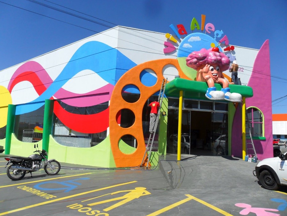 Fachada colorida da Vila Alegria com design vibrante e escultura.