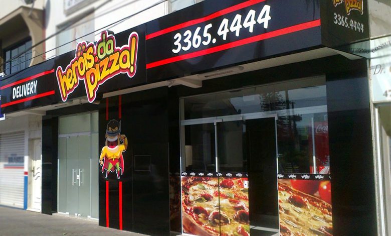 Fachada de pizzaria "Heróis da Pizza" com design vibrante.