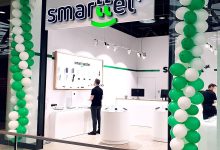 Fachada de loja de celular decorada com balões verdes e brancos.