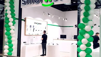 Fachada de loja de celular decorada com balões verdes e brancos.