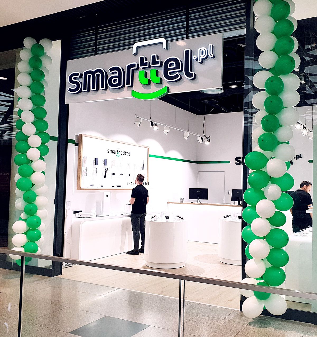 Fachada de loja de celular decorada com balões verdes e brancos.