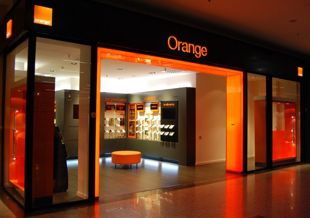 Loja Orange com design moderno, interior iluminado e tons laranja.