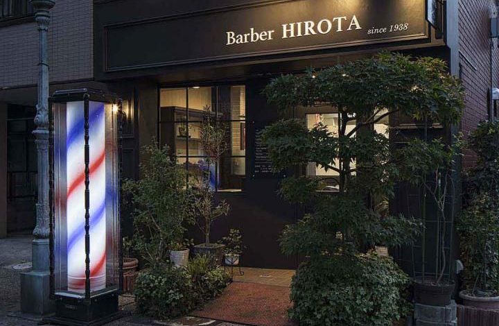 Fachada moderna de barbearia com placa preta e letras brancas.