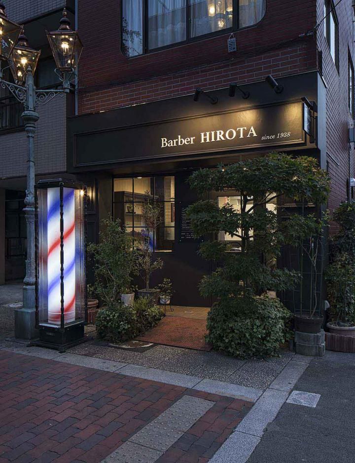 Fachada moderna de barbearia com placa preta e letras brancas.
