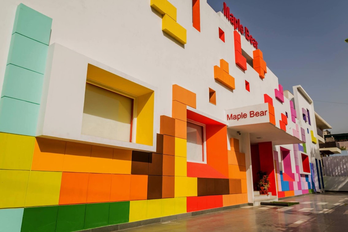 Fachada colorida de loja Maple Bear com design geométrico e moderno.