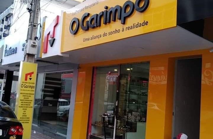 Fachada da "O Garimpo" com letreiro amarelo vibrante e informativo.