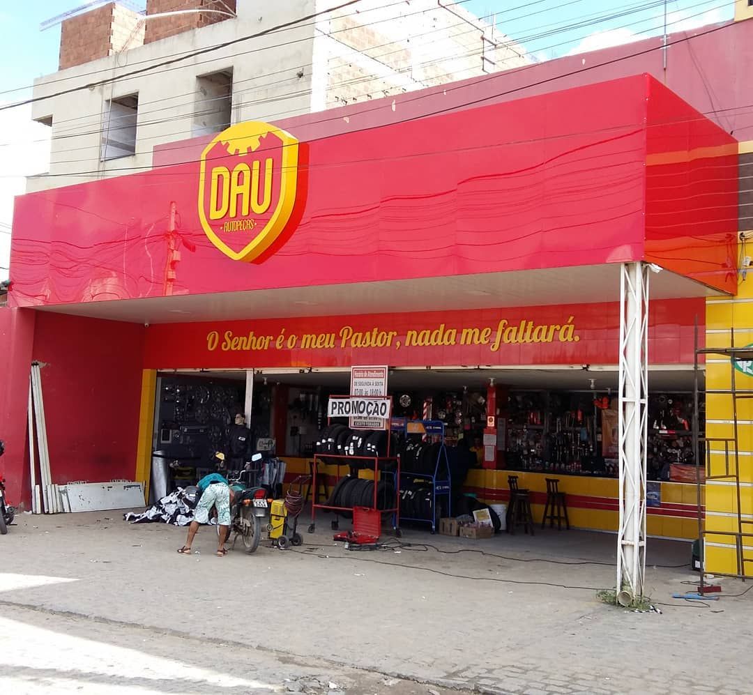 Fachada da "DAU Autopeças" com letreiro vermelho e amarelo vibrante.