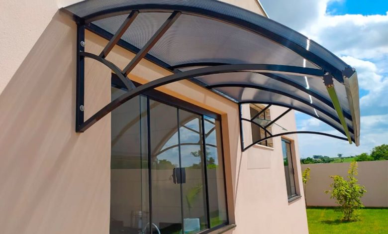 Toldo Fixo policarbonato curvo instalado sobre entrada, sustentado por estrutura metálica moderna.