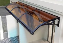 Toldo de policarbonato curvo com estrutura metálica instalado sobre entrada.