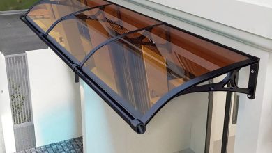 Toldo de policarbonato curvo com estrutura metálica instalado sobre entrada.