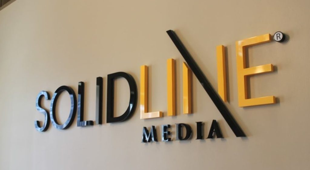 Logo tridimensional em acrílico da empresa SOLIDLINE MEDIA em preto e amarelo.