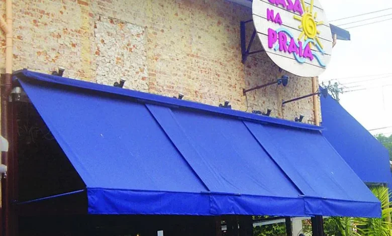 Toldo retrátil azul instalado em uma fachada comercial
