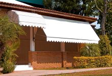 Toldo retrátil branco sombreando varanda de casa com fachada de tijolos