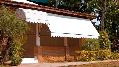 Toldo retrátil branco sombreando varanda de casa com fachada de tijolos