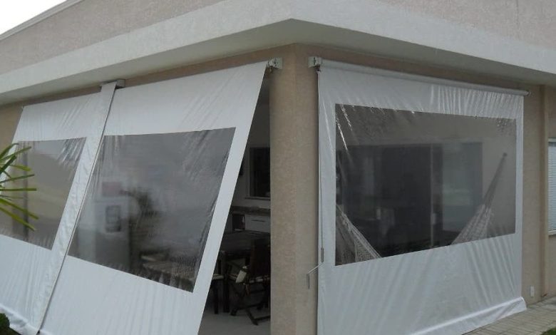 Toldo branco com janelas transparentes em varanda de casa moderna.