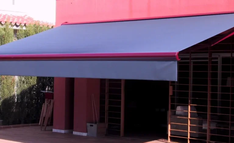Toldo azul e vermelho instalado em varanda de residência moderna.