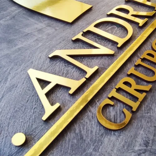 Chave dourada com inscrição decorativa em superfície cinza texturizada.