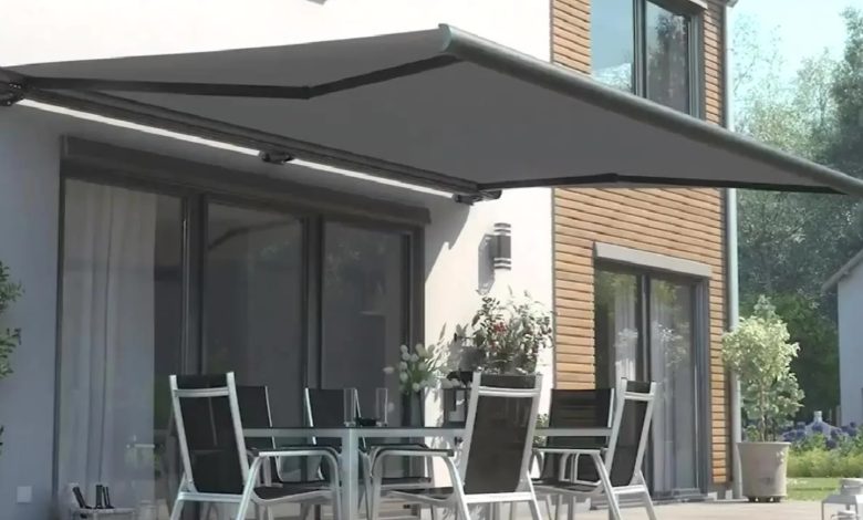 Toldo cinza cobre mesa com cadeiras em área externa residencial.