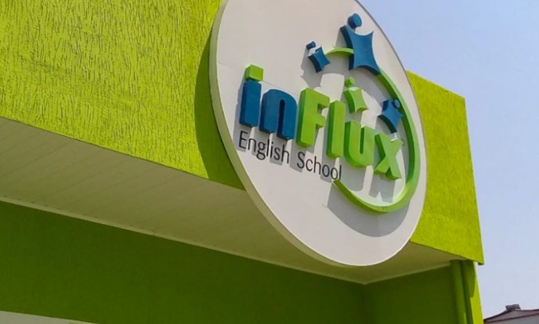 Fachada verde da inFlux English School com logotipo circular estilizado.