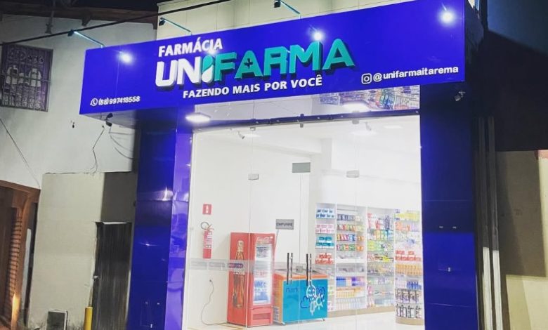 Fachada de farmácia Unifarma com letreiro azul e iluminação noturna.
