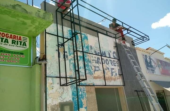 Placa comercial verde com logotipo para negócio local na Aclimação.