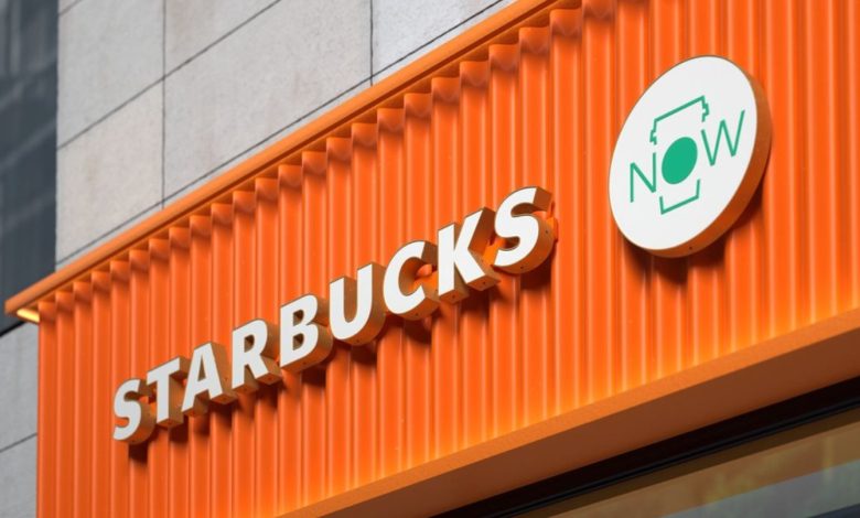 Placa comercial moderna da Starbucks em fachada laranja vibrante vertical.